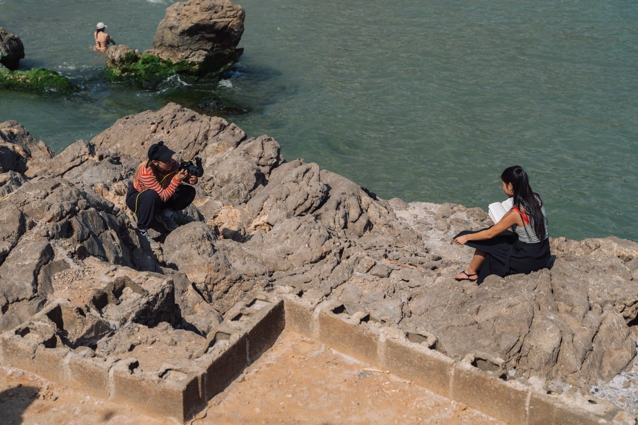 Eine Fotografin fotografiert ein Model auf Felsen in Barcelona